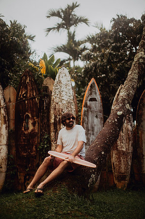 simsearch:6109-08929136,k - Mid adult male skateboarder sitting on tree trunk by old surfboard structure in park, Haiku, Hawaii, USA Stockbilder - Premium RF Lizenzfrei, Bildnummer: 614-09270192