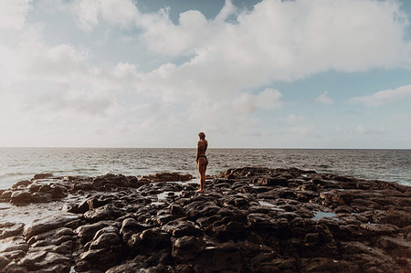 Swimmer standing on rocks by sea, Princeville, Hawaii, US Stock Photo - Premium Royalty-Free, Code: 614-09270206