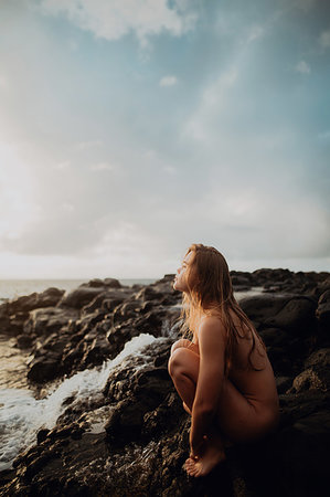 Naked woman sitting on rocks by sea, Princeville, Hawaii, US Photographie de stock - Premium Libres de Droits, Code: 614-09270212