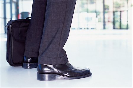 Briefcase and feet of businessman Stock Photo - Premium Royalty-Free, Code: 614-00388971