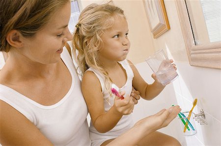 Mother helping daughter brush teeth Stock Photo - Premium Royalty-Free, Code: 614-00391628