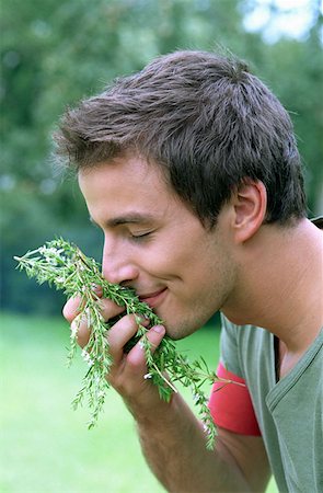 Young man smelling rosemary Stock Photo - Premium Royalty-Free, Code: 614-00599413
