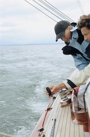 Couple turning crank handle on boat Stock Photo - Premium Royalty-Free, Code: 614-00602702