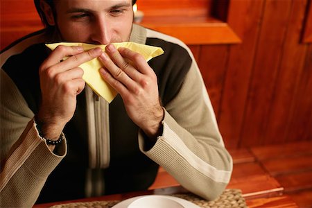Man wiping his mouth with napkin Stock Photo - Premium Royalty-Free, Code: 614-00602947