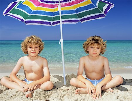 Twin boys under a sun umbrella Stock Photo - Premium Royalty-Free, Code: 614-00654881