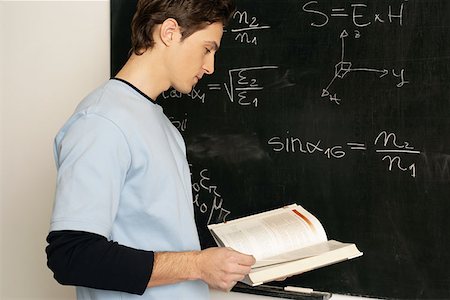 Young man standing in front of a blackboard Stock Photo - Premium Royalty-Free, Code: 614-00655601