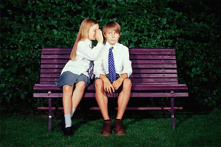 Girl whispering to boy on bench Stock Photo - Premium Royalty-Free, Code: 614-00658805