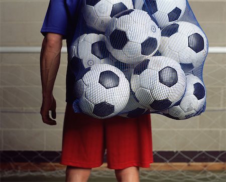 Footballer holding a bag of footballs Stock Photo - Premium Royalty-Free, Code: 614-00652798