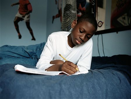 Boy doing homework on bed Stock Photo - Premium Royalty-Free, Code: 614-00653409