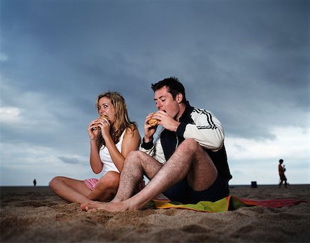 Couple eating hamburgers on beach Stock Photo - Premium Royalty-Free, Code: 614-00653734