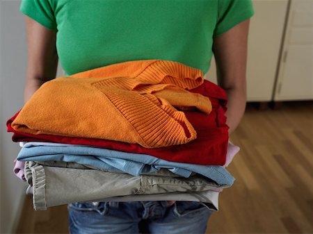 Woman holding pile of clothes Stock Photo - Premium Royalty-Free, Code: 614-00694753