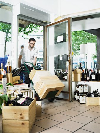 pushing door - Man pushing trolley of wine boxes into shop Stock Photo - Premium Royalty-Free, Code: 614-00777491