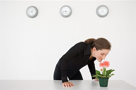 flower bending over - Businesswoman smelling a flower Stock Photo - Premium Royalty-Free, Code: 614-00913059