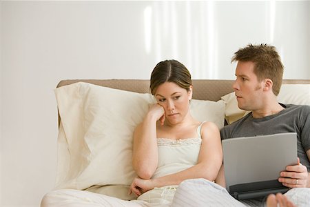Wife annoyed at husband using laptop in bed Stock Photo - Premium Royalty-Free, Code: 614-00913795