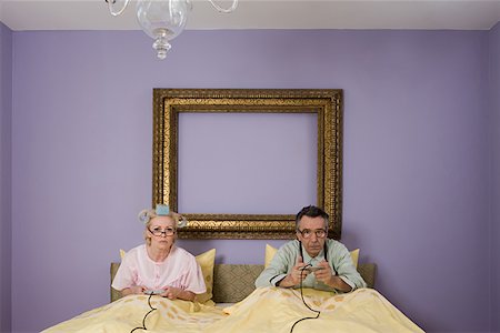 Senior couple playing video game in bed Stock Photo - Premium Royalty-Free, Code: 614-01028110
