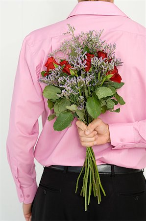Man hiding flowers behind back Stock Photo - Premium Royalty-Free, Code: 614-01270040