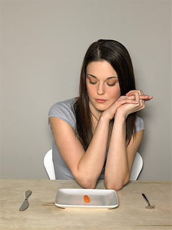 Young woman with carrot on a plate Stock Photo - Premium Royalty-Free, Code: 614-01486575