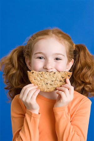 simsearch:614-02258138,k - Girl holding a cookie over her mouth Stock Photo - Premium Royalty-Free, Code: 614-01559196