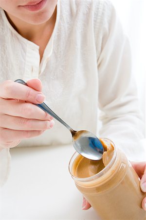 peanut butter woman - Woman scooping peanut butter from jar Stock Photo - Premium Royalty-Free, Code: 614-01560897