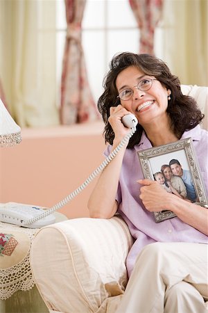 Woman on telephone with picture of family Stock Photo - Premium Royalty-Free, Code: 614-01757367