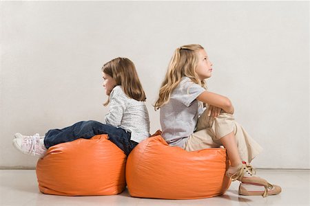 sister back to back - Sisters sat back to back on beanbags Stock Photo - Premium Royalty-Free, Code: 614-01758356