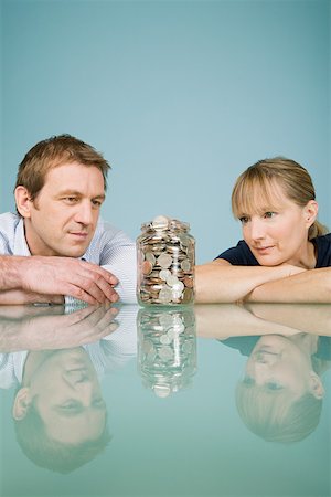 Couple looking at jar of coins Stock Photo - Premium Royalty-Free, Code: 614-01870037