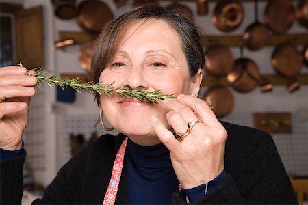 Woman smelling a sprig of rosemary Stock Photo - Premium Royalty-Free, Code: 614-02049362