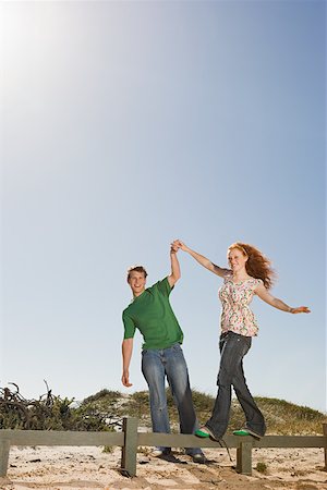 Un jeune homme aidant une femme en équilibre sur une clôture Photographie de stock - Premium Libres de Droits, Code: 614-02049764