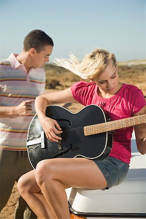 A young woman playing a guitar and a young man Stock Photo - Premium Royalty-Free, Code: 614-02049783