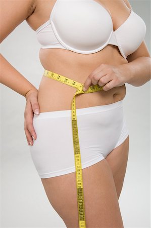 A woman measuring her waist Stock Photo - Premium Royalty-Free, Code: 614-02050680