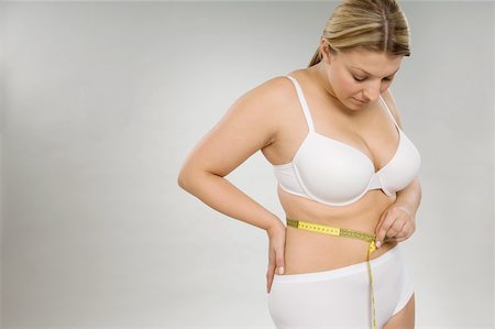 A woman measuring her waist Stock Photo - Premium Royalty-Free, Code: 614-02050713