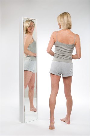 A woman looking in a mirror Stock Photo - Premium Royalty-Free, Code: 614-02050755