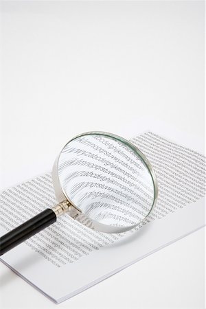 Magnifying glass and a stack of paper Stock Photo - Premium Royalty-Free, Code: 614-02074335
