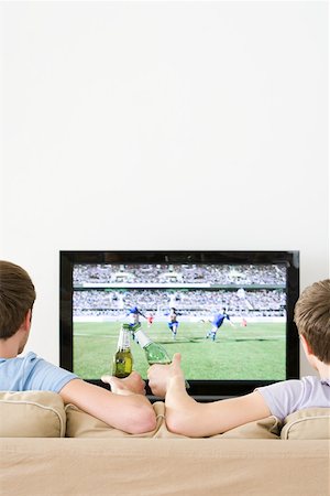 Two young men watching football on the tv Stock Photo - Premium Royalty-Free, Code: 614-02074952