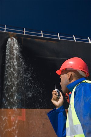 A harbour worker using a walkie talkie Stock Photo - Premium Royalty-Free, Code: 614-02073978