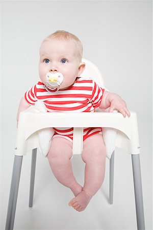 A baby girl sat in a high chair Foto de stock - Royalty Free Premium, Número: 614-02243218