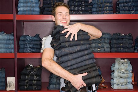 Man holding a stack of jeans Stock Photo - Premium Royalty-Free, Code: 614-02392290