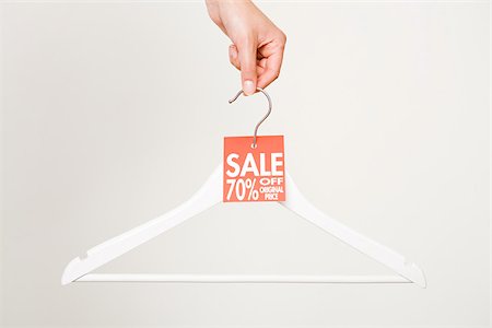 price tag - Woman holding a clothes hanger Stock Photo - Premium Royalty-Free, Code: 614-02392356