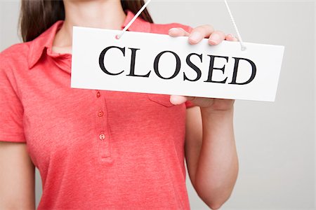 Woman holding a closed sign Stock Photo - Premium Royalty-Free, Code: 614-02392382