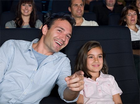 photo of theatre audience laughing - Father and daughter watching a movie Stock Photo - Premium Royalty-Free, Code: 614-02392983