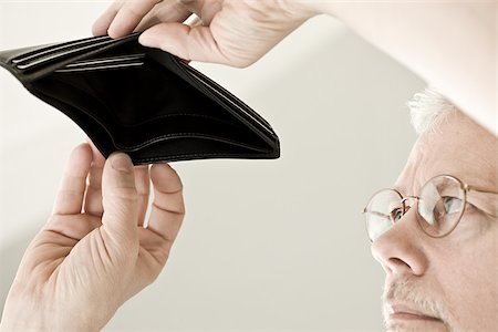 dettes - Un homme à la recherche dans un porte-monnaie vide Photographie de stock - Premium Libres de Droits, Code: 614-02393222