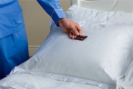 simsearch:614-02612546,k - A man putting a chocolate on a pillow Stock Photo - Premium Royalty-Free, Code: 614-02393485