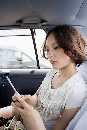 Young woman in cab with cellphone Stock Photo - Premium Royalty-Free, Code: 614-02680916