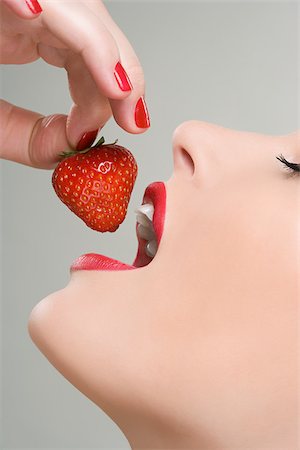 people with fruits cutout - Woman eating a strawberry Stock Photo - Premium Royalty-Free, Code: 614-02740386