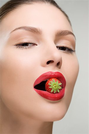 Jeune femme avec une fraise dans sa bouche Photographie de stock - Premium Libres de Droits, Code: 614-02740410