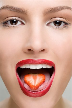 Woman with a slice of strawberry on her tongue Stock Photo - Premium Royalty-Free, Code: 614-02740425