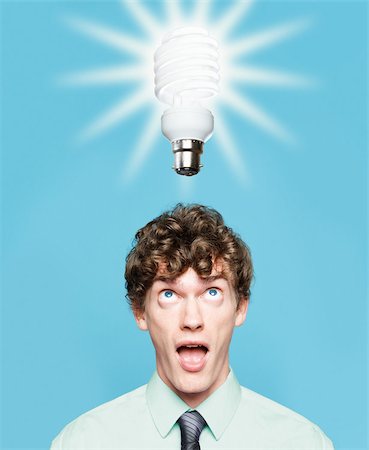 A young man looking at an energy saving lightbulb Stock Photo - Premium Royalty-Free, Code: 614-02763815