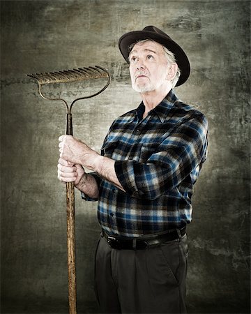 farmer looks up - Portrait of a farmer holding a rake Stock Photo - Premium Royalty-Free, Code: 614-02763987