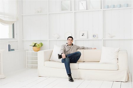 family room hispanic - Hispanic man relaxing on a sofa Stock Photo - Premium Royalty-Free, Code: 614-02934916