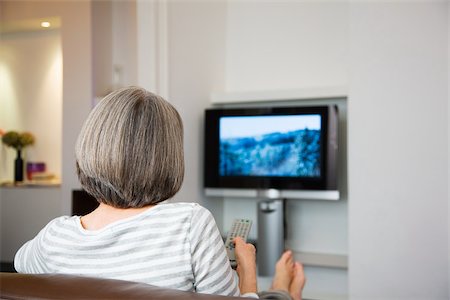 Mature woman watching television Stock Photo - Premium Royalty-Free, Code: 614-02933891